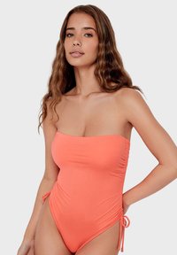 Strapless een-delig badpak in heldere koraalkleur, met zijkant fronsing en verstelbare strikjes, gemaakt van soepele, rekbare stof.