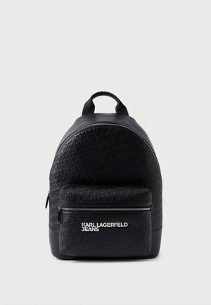 Melnā mugursoma ir ar teksturētu virsmu, apaļu formu, priekšējo rāvējslēdzēja kabatu un baltu zīmolu. Izgatavota no sintētiskā materiāla ar divām rokturiem.