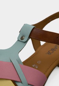 Πολύχρωμο σανδάλι με μπλε ανοιχτό λουράκι μπροστά, ροζ μεσαίο λουράκι και καφέ πίσω λουράκι με διακοσμητικό εξάρτημα. Λείο υλικό.