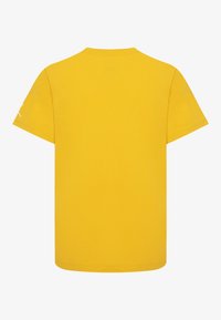 Żółta bawełniana koszulka z krótkimi rękawami i okrągłym dekoltem. Na lewym rękawie znajduje się małe logo. Gładka tekstura, regularny krój.