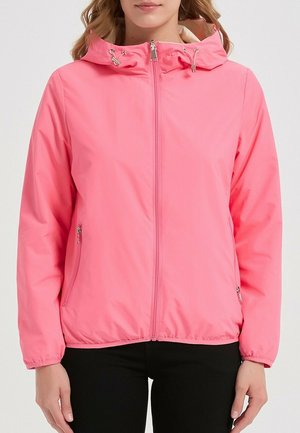 Femme portant une veste à capuche rose vif avec fermeture éclair à l'avant et poches zippées sur les côtés, debout devant un fond uni.