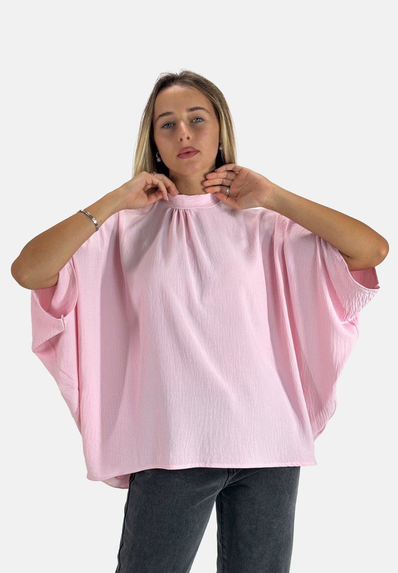 Maglietta rosa comoda con un collo alto, ampie maniche a pipistrello e una finitura testurizzata. Abbinata a pantaloni grigio scuro.