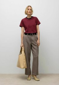 Bordeaux t-shirt, beige geruite broek, zwarte riem, beige handtas en beige hakken. Soepele stof, relaxte pasvorm en ruitpatroon op de broeken.