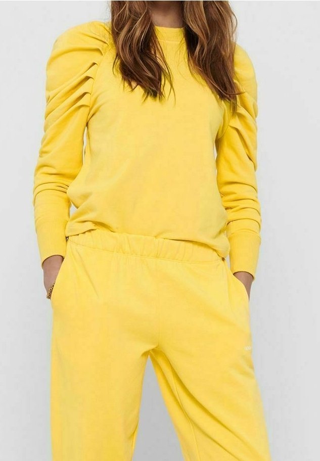 Sudadera amarilla con mangas abullonadas, material de algodón suave; combinada con pantalones deportivos amarillos a juego con cintura elástica.