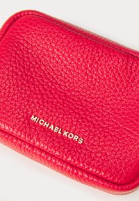 Red pebbled leather wallet featuring a gold logo on the front, with a smooth rounded edge design and textured surface.