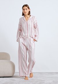 Pasiasty, lekki zestaw piżamowy w kolorze różowym i białym. Zawiera koszulę zapinaną na guziki oraz spodnie ze sznurkiem w talii, o luźnym kroju i długich rękawach.