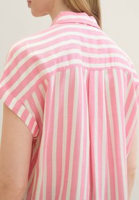 Pink and white striped shirt with short sleeves, collar, and back pleat detail. Fabric appears soft with a smooth texture.