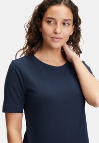 Granatowa bawełniana koszulka z okrągłym dekoltem i krótkimi rękawami, o gładkiej fakturze i dopasowanym kroju, zaprojektowana z myślą o komforcie.