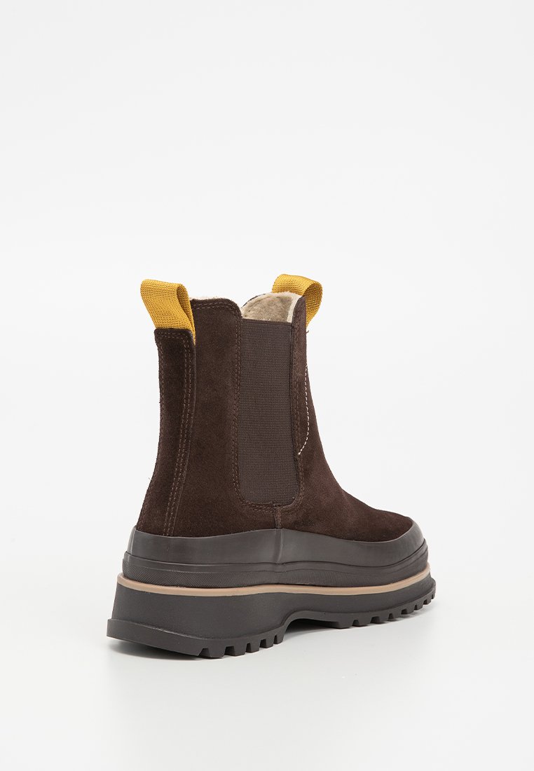 Bruna mockaskinnankelboots med gula dragflikar, elastiska sidopaneler och en tjock gummisula. Texturerad yta och robust design.