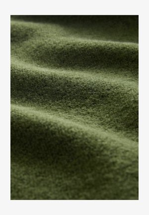 Textured green fabric with a soft, fuzzy surface, showcasing ripples and folds that create depth and visual interest.