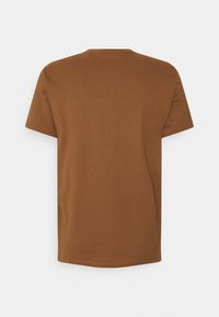 Camiseta de algodón marrón con mangas cortas, escote redondeado y un corte holgado. Textura suave y color sólido sin patrones ni decoraciones.