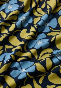 Țesătură multicoloră cu un model floral, având flori albastre și galbene pe un fundal întunecat de navy. Material moale din bumbac texturat.