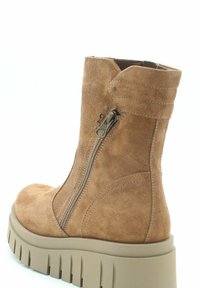 Tan suède enkellaars met een rits aan de zijkant, chunky beige buitenzool en subtiele stiksels. Voorzien van een ronde neus en een gemeleerde textuur.