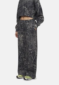 Afgesneden sweatshirt en losse broek in een grijs camouflagepatroon, gemaakt van zachte stof. Voorzien van een elastische tailleband en zijzakken.