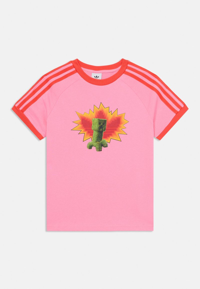 Rožinė medvilninė marškinė su raudonomis dryžuotomis rankovėmis, kuriose pavaizduotas žalias pikseliuotas veikėjas prieš geltoną sprogimo foną.