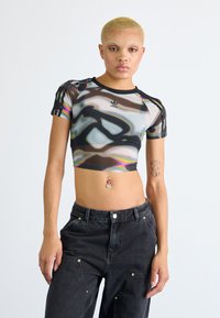 Black and multicolored mesh crop top with a round neckline, short sleeves, and Adidas logo on the chest, paired with high-waisted dark jeans.