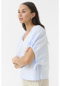 Light blue and white striped blouse with a V-neck, puff sleeves, and tie details at the waist. Made from lightweight fabric.