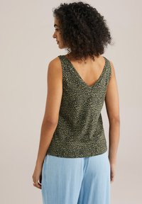 Green leopard print top with a V-neck design, made of soft material. The back features a similar pattern, paired with light blue pants.