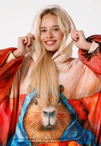 Kapuce ar lielizmēra segu no mīksta materiāla, kuras dizainā ir krāsains mājas bebriņa seja zilā kapucē. Silts sarkana un oranža gradienta dizains.