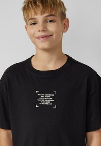 Zwart katoenen t-shirt met witte tekst met zinnen en een grafiek van een doos. Ronde hals, korte mouwen, zachte textuur, comfortabele pasvorm.