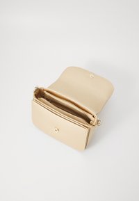 Sac à main en cuir beige avec un rabat, doté d'un fermoir à pression doré et de deux compartiments intérieurs avec des détails zippés. Fini texturé.