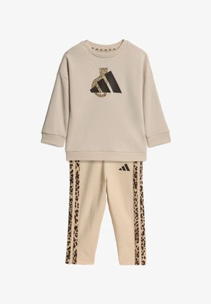 Conjunto beige de sudadera de manga larga y pantalones con rayas de estampado de leopardo y un leopardo integrado en un gran logo negro en la parte superior.