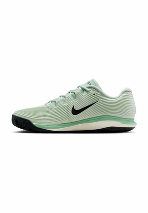 Lichtgroene Nike sportschoen met zwarte swoosh-logo, gestructureerde bovenkant, groene tussenzool en zwarte buitenzool, gezien vanuit de zijkant.