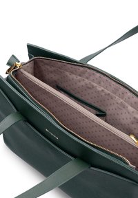 Grüne Ledertasche mit zwei Tragegriffen, einem Reißverschluss und einem hellrosa Innenfutter mit gepunktetem Muster sowie mehreren Fächern.