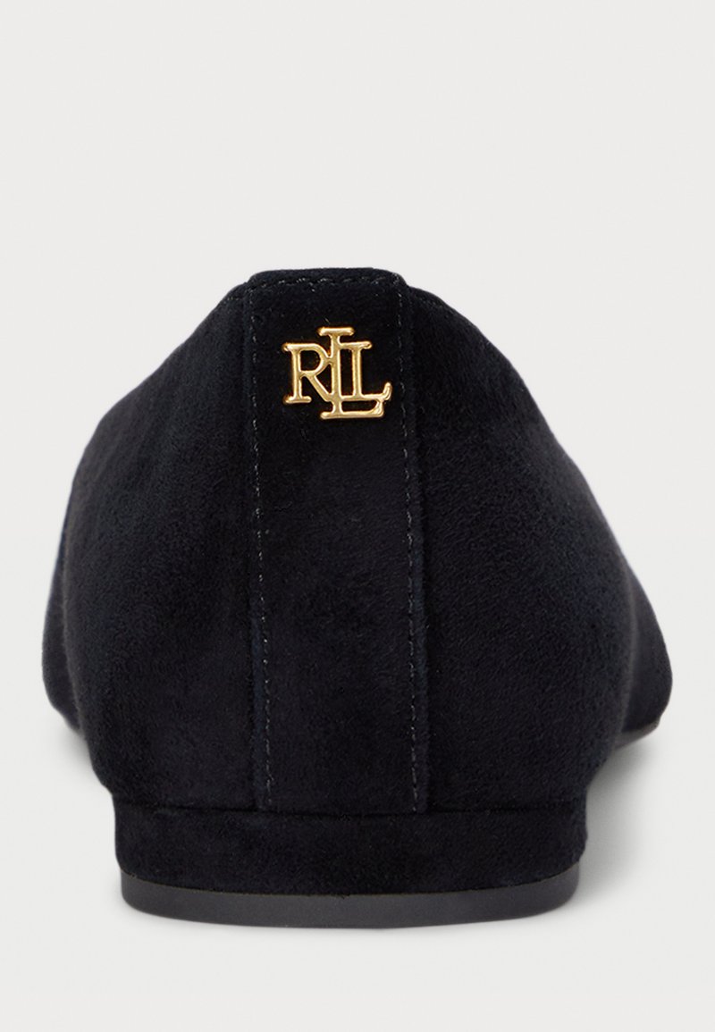 Schwarze Wildleder-Ballettflats mit einer abgerundeten Zehe und einem goldenen Logo-Akzent auf der Ferse, ausgestattet mit einer matten Textur und einer flachen Gummisohle.
