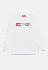 Hosszú ujjú fehér póló, pamutból készült, nagy fekete és piros "DIESEL" logóval, enyhe csillogó hatással. Egyszerű kerek nyakú kialakítás.