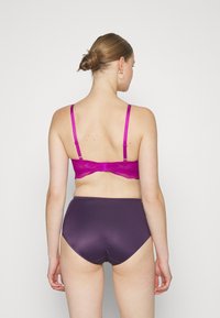 Lace-back bralette i lys rosa med justerbare stropper, kombinert med høylivet lilla undertøy med en glatt tekstur og sømløs finish.