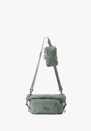 Sac en nylon vert à bandoulière réglable, design enroulable, poche zippée et deux accents ronds à l'avant.