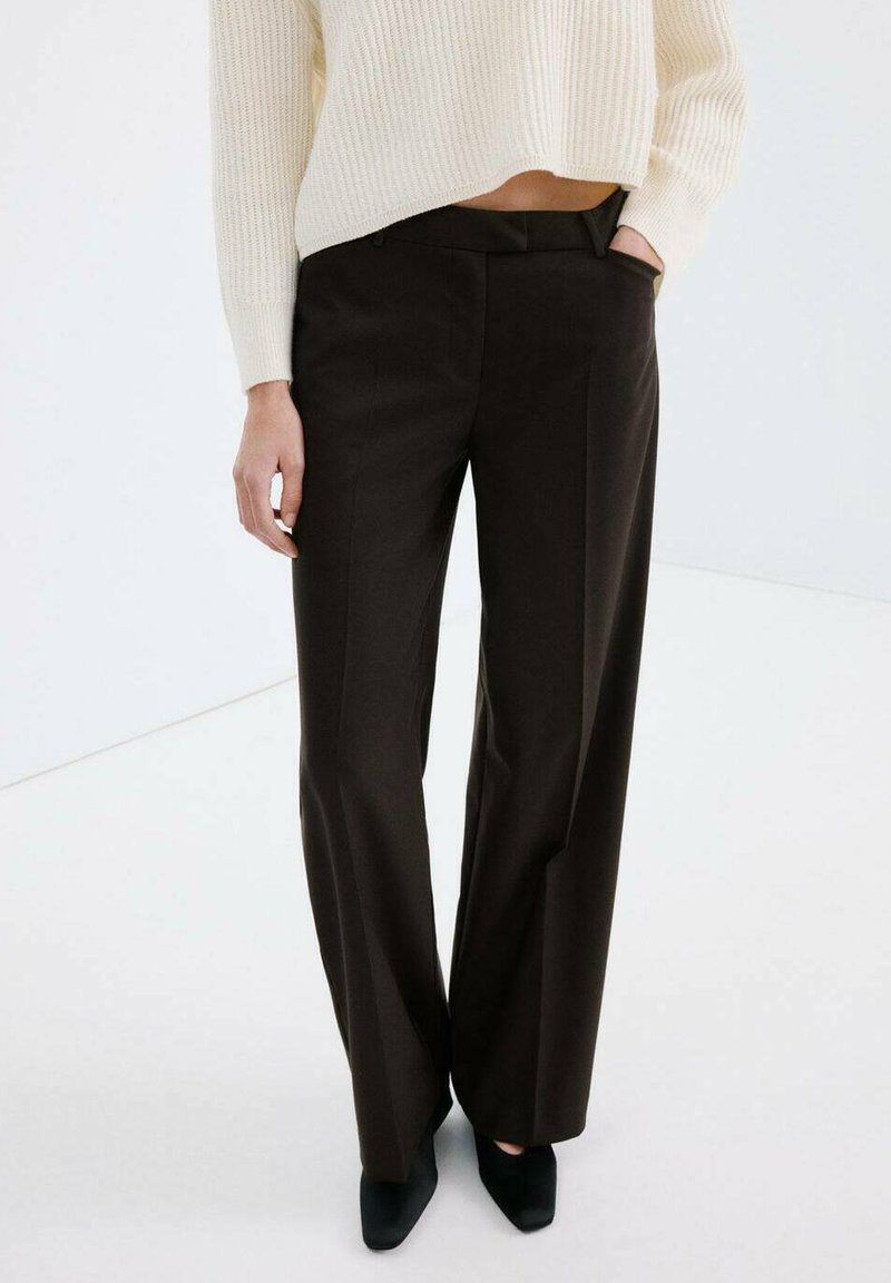 Pantalon marron sur mesure à coupe droite, avec une texture lisse, des poches avant et une taille mi-haute, associé à un pull crème.