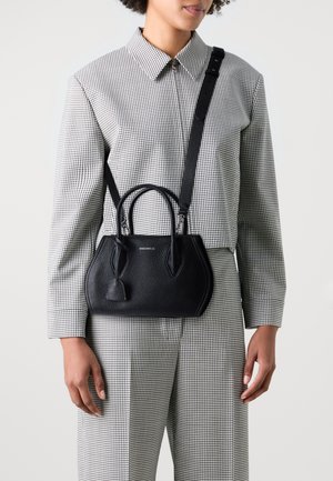 Schwarze Lederhandtasche mit strukturierter Oberfläche, zwei Griffen und einem verstellbaren Schulterriemen. Mit einer detaillierten Quaste und einer strukturierten Silhouette.