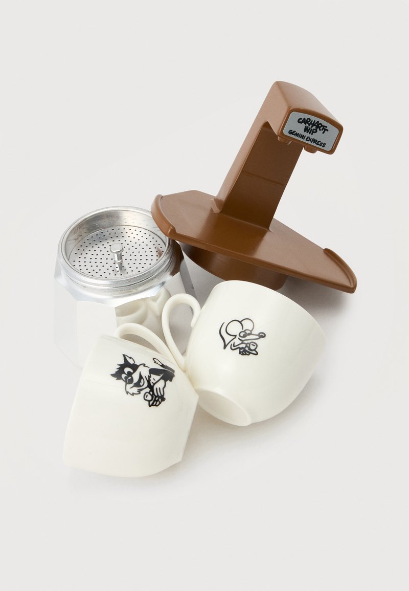 Zwei weiße Keramiktassen mit schwarzen Cartoon-Mausmotiven, eine silberne Metallkaffeemaschine und ein brauner Kunststoff-Kaffeefilterhalter mit "Carhartt WIP Gemini Express" Etikett.