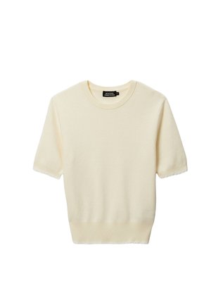 Pull à manches courtes en crème, fabriqué en tissu doux, avec un col rond et des bords festonnés aux poignets et à l'ourlet.