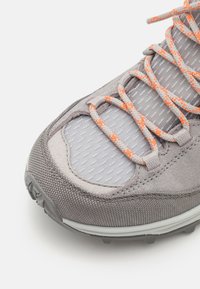 Grauer Sportschuh mit samtiger Oberseite, Netz-Einsatz und orangen Akzenten. Verfügt über dicke Schnürsenkel und eine robuste Sohle für besseren Halt.