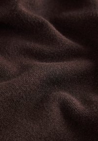 Brown fabric with a textured surface, displaying soft, fine fibers and gentle waves, indicating a lightweight and textured material.