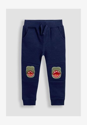 Námořnické modré tepláky s elastickým pasem, dvěma bočními kapsami a aplikacemi zelených monster s červenými ústy na úrovni kolen.