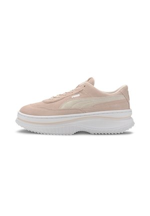 Beiger Puma Veloursleder-Sneaker mit dicker weißer gerillter Sohle und weißem Puma-Logo an der Seite, von der Außenseite betrachtet.