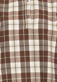 Chemise à carreaux marron, beige et blanc avec col boutonné et détails de couture visibles sur un tissu en coton.