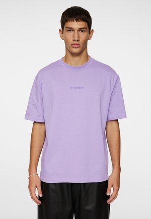 Lavendel farvet bomulds T-shirt med korte ærmer, rund hals og et subtilt logo trykt på brystet. Glat tekstur og afslappet pasform.