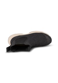 Botín negro de ante con un acabado texturizado, suela beige en contraste, paneles elásticos y una lengüeta en la parte posterior para facilitar su uso.