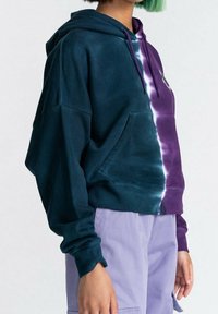 Sudadera con capucha que presenta un degradado de verde oscuro a púrpura, efecto teñido anudado, tela suave y un bolsillo tipo canguro.