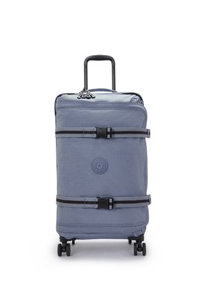 Soft-shell suitcase in light blue fabric, featuring a telescopic handle, four wheels, and clip straps. Circular logo on the front.