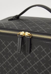 Black textured faux leather cosmetic bag with gold zipper and pulls. Features a geometric pattern and a top handle for easy carrying.