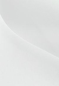 Deux morceaux de tissu blanc superposés montrant des surfaces lisses et légèrement texturées avec des courbes douces et des ombres.