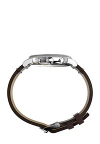 Montre en acier inoxydable avec une lunette argentée, un bracelet en cuir marron et une couronne texturée. Inclut deux boutons-poussoirs sur le côté.