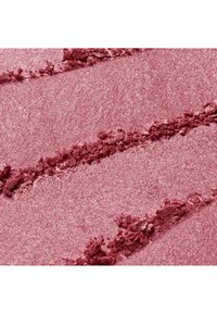 Poudre rose broyée scintillante avec des lignes texturées rugueuses sur une surface rose lisse, ressemblant à du maquillage ou de la poudre de pigment.