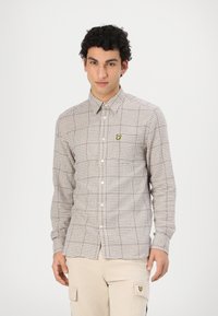 Brązowa i biała koszula w kratę z guzikiem, z kołnierzykiem i żółtym haftowanym logo na piersi. Slim fit, długie rękawy i bawełniany materiał.